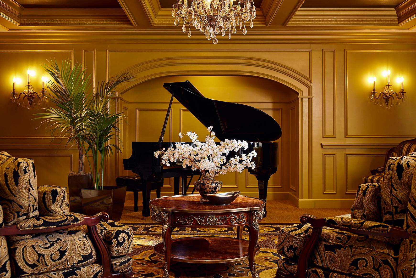 An elegant lobby with a baby grand and fresh floral arrangements
