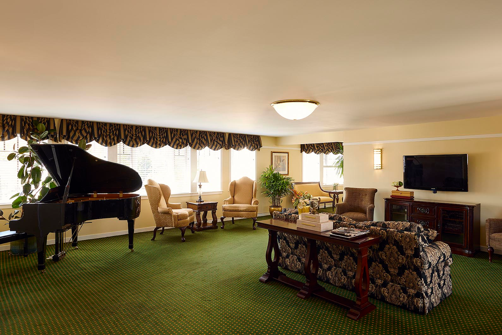 A baby grand piano, TV screen and seating in the sitting room