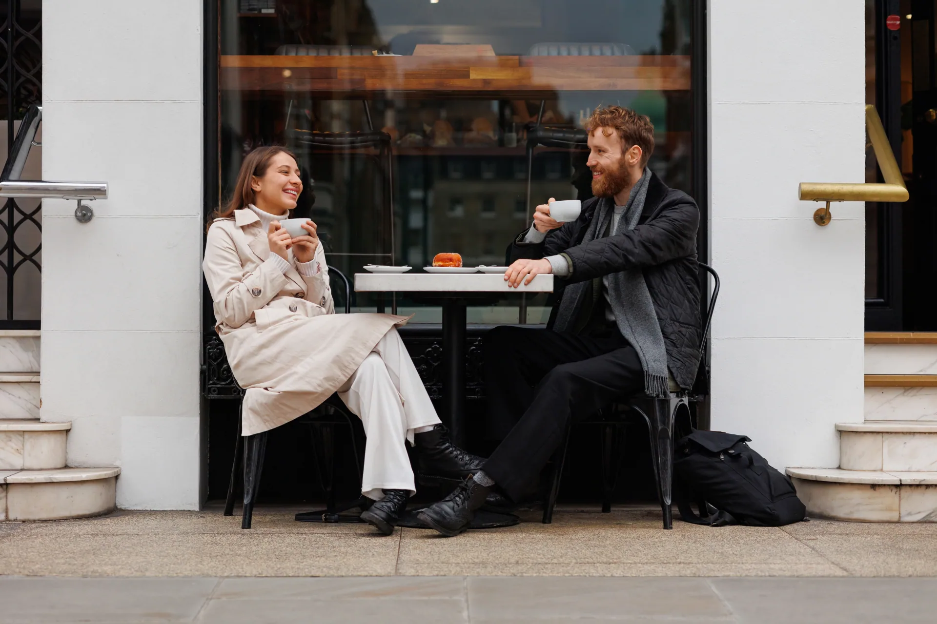 Couple on a date sitting outside a coffee shop and drinking coffee