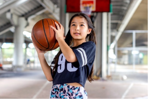 A little girl holding a basketball while playing