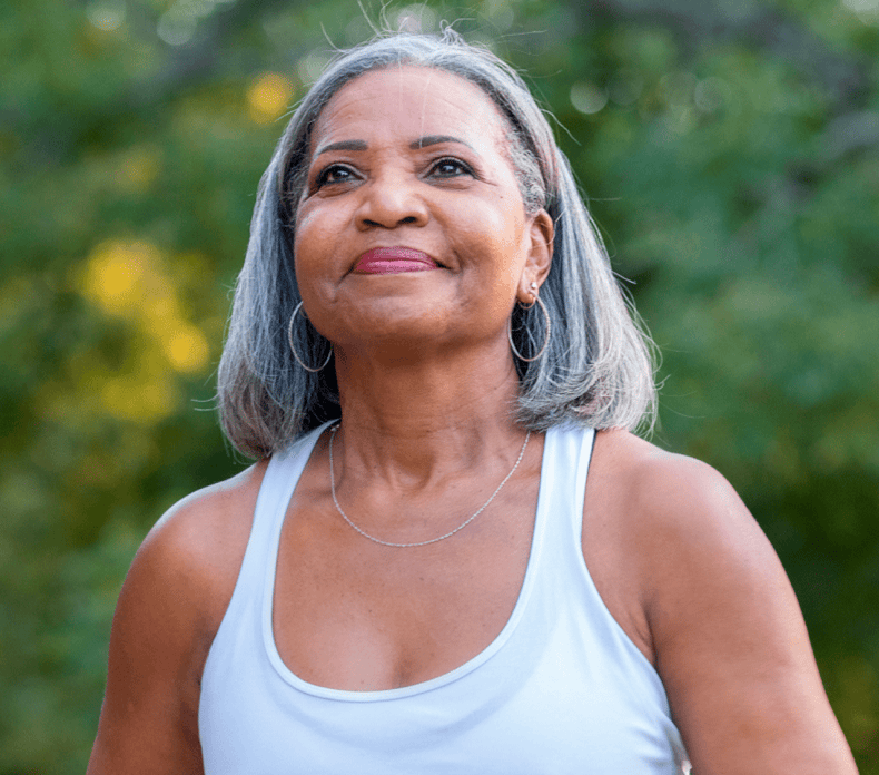 Grey haired Black lady wearing a white tank top