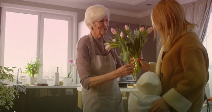 Elderly lady receiving flowers from another