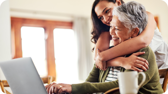 Woman hugging older woman looking at the computer