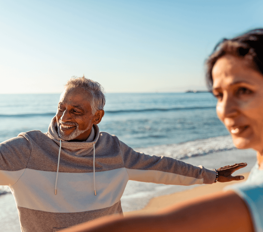 Two people with arms stretched on a beach