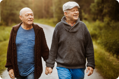 Two older men holding hands on a walk