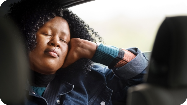 A lady asleep in the backseat of a car