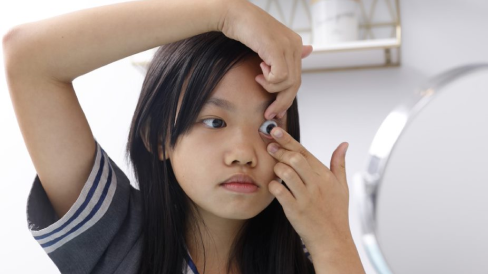 Jeune enfant qui met une lentille cornéenne 