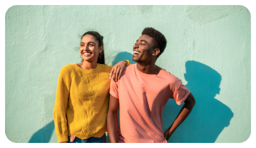Young interracial couple smiling against a green wall