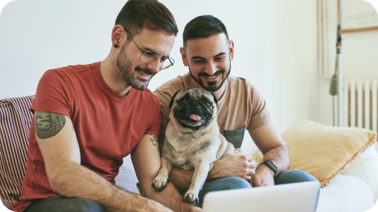 Zwei Personen und ein Mops, die auf einen Laptopbildschirm schauen