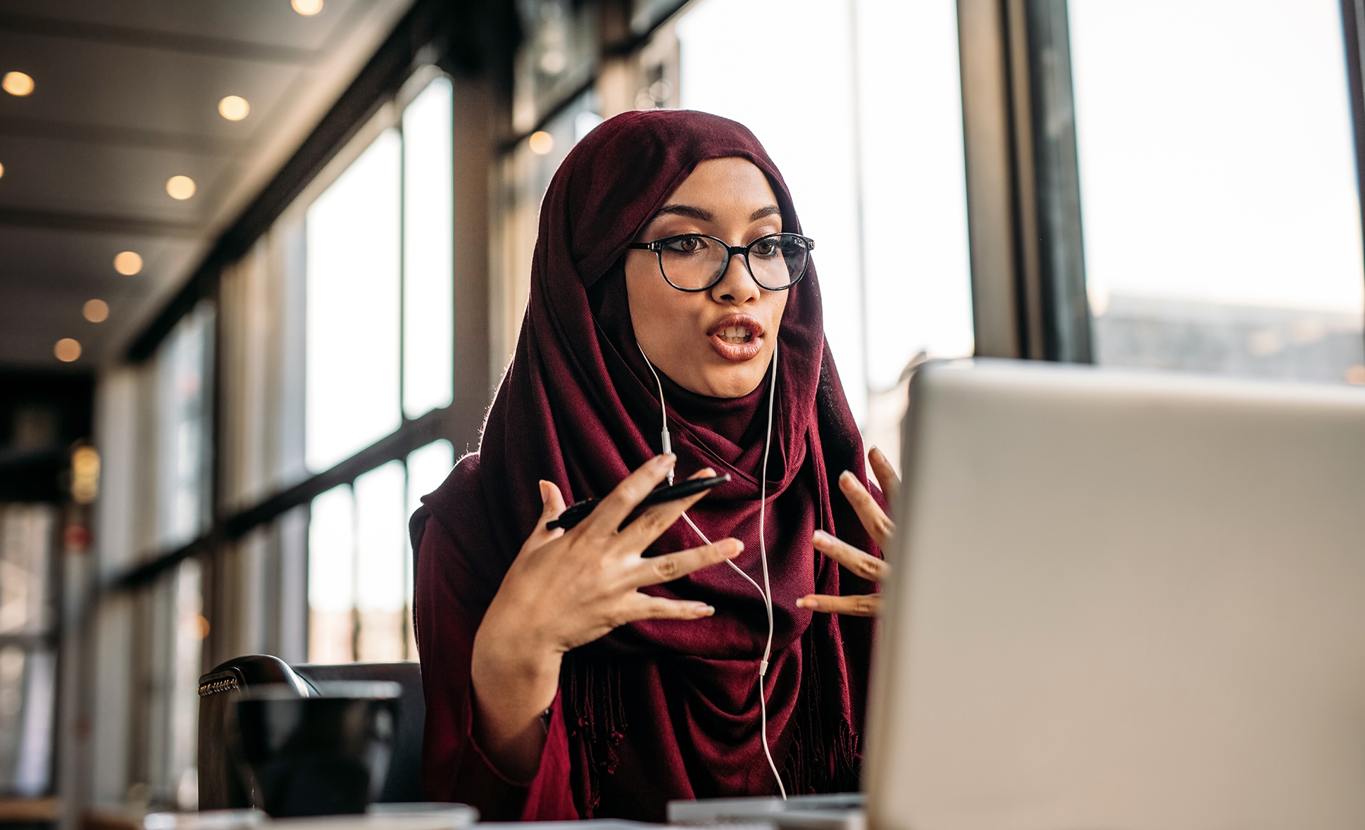 Woman in front of a laptop talking to her instructor during an online language course