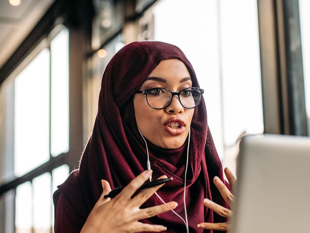Woman in front of a laptop talking to her instructor during an online language course