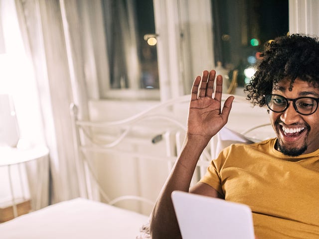 Man holding a tablet and waving at his instructor at the beginning of his online language class