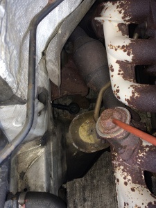An image showing the relative location of the idler arm- the bushing assembly is under a steel heat shield in this W124.
