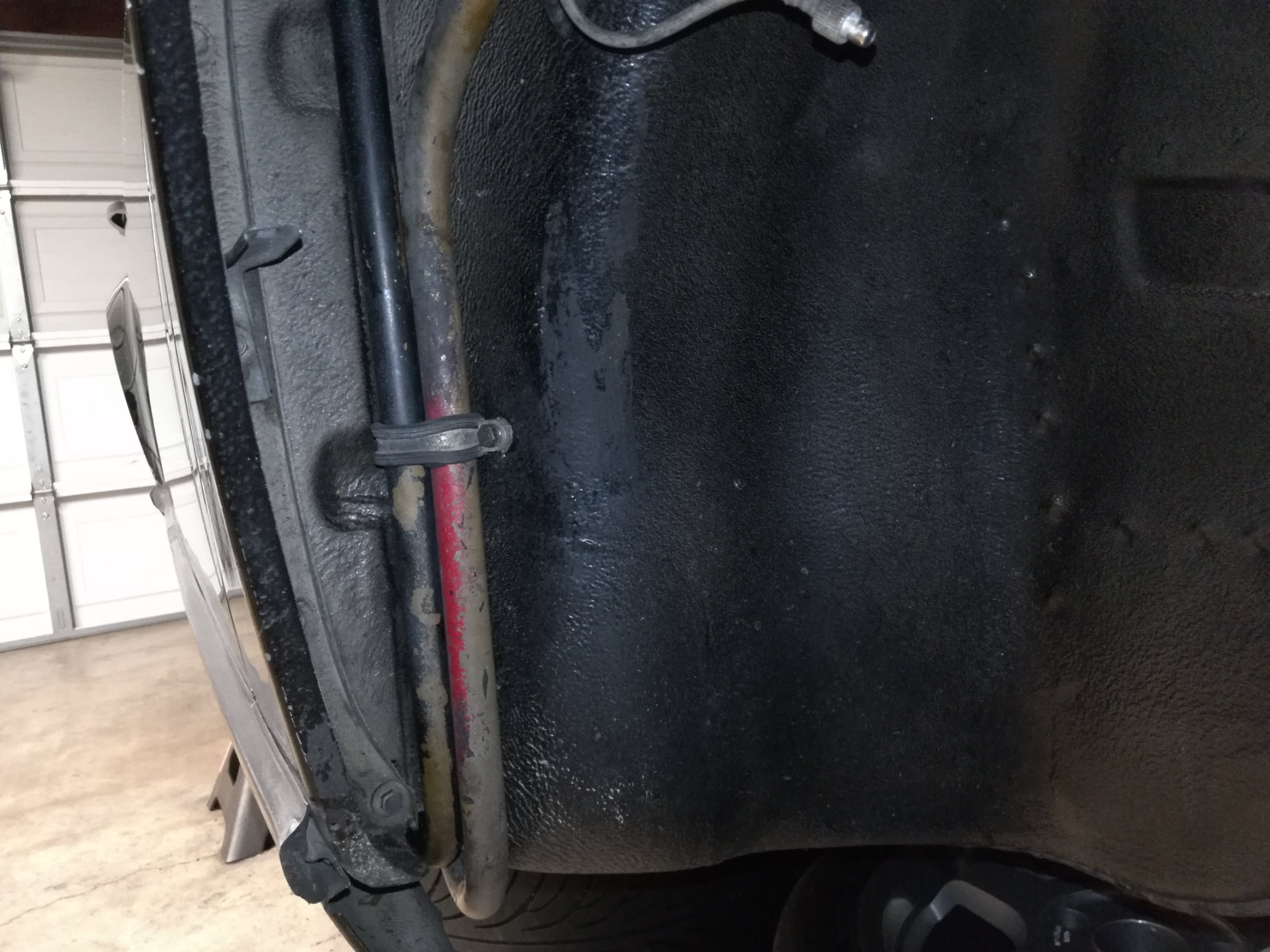 Air-cooled Porsche 911 hard oil line clamp under front fender well.