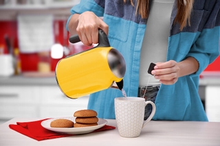 Someone pouring water from a kettle to make tea