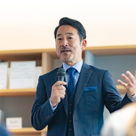 Man in a federal position holding a microphone and talking confidently in French