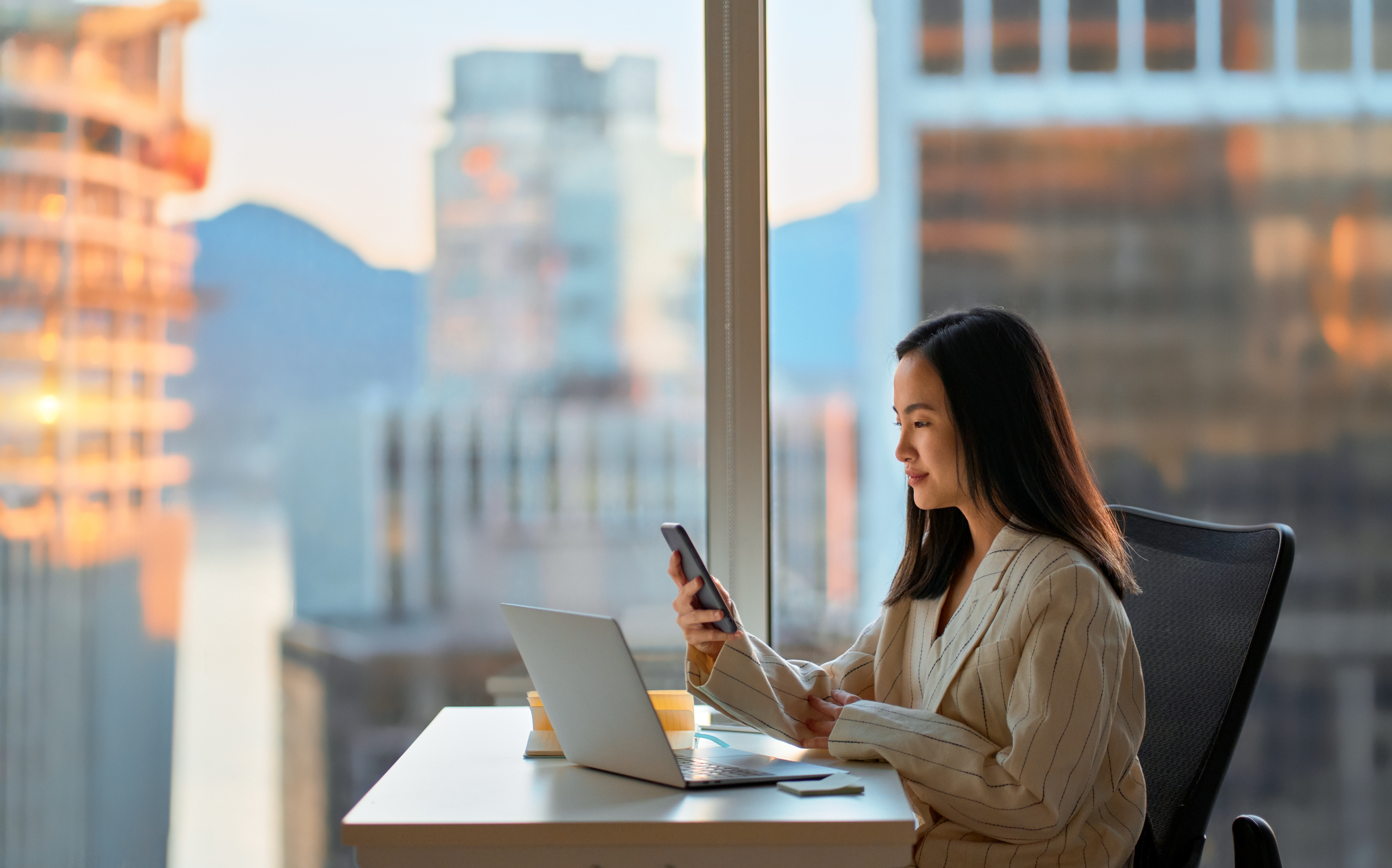 Woman with a phone and a laptop learning about how business is conducted in different cultures with Berlitz's Cultural Navigator