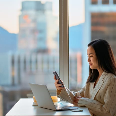 Woman with a phone and a laptop learning about how business is conducted in different cultures with Berlitz's Cultural Navigator