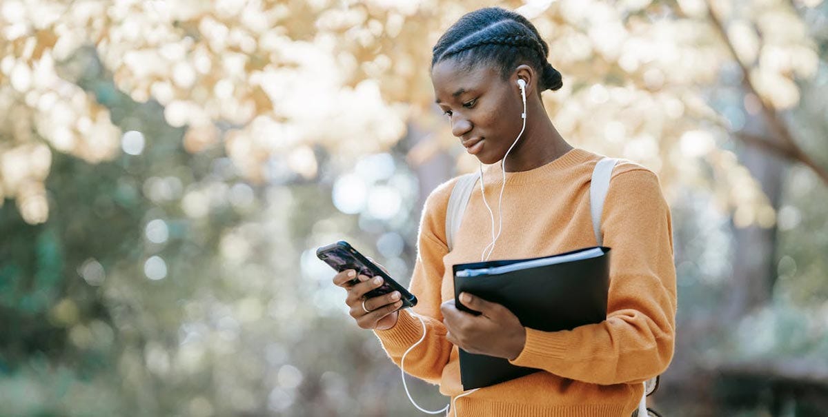 Student with headphones listening a Spanish talk on their phone