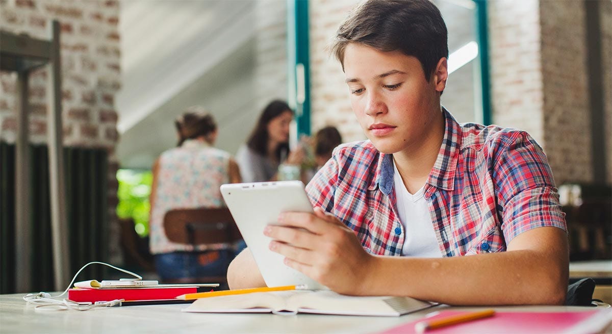Schoolboy looking at his tablet and learning about the basics of gender in Spanish