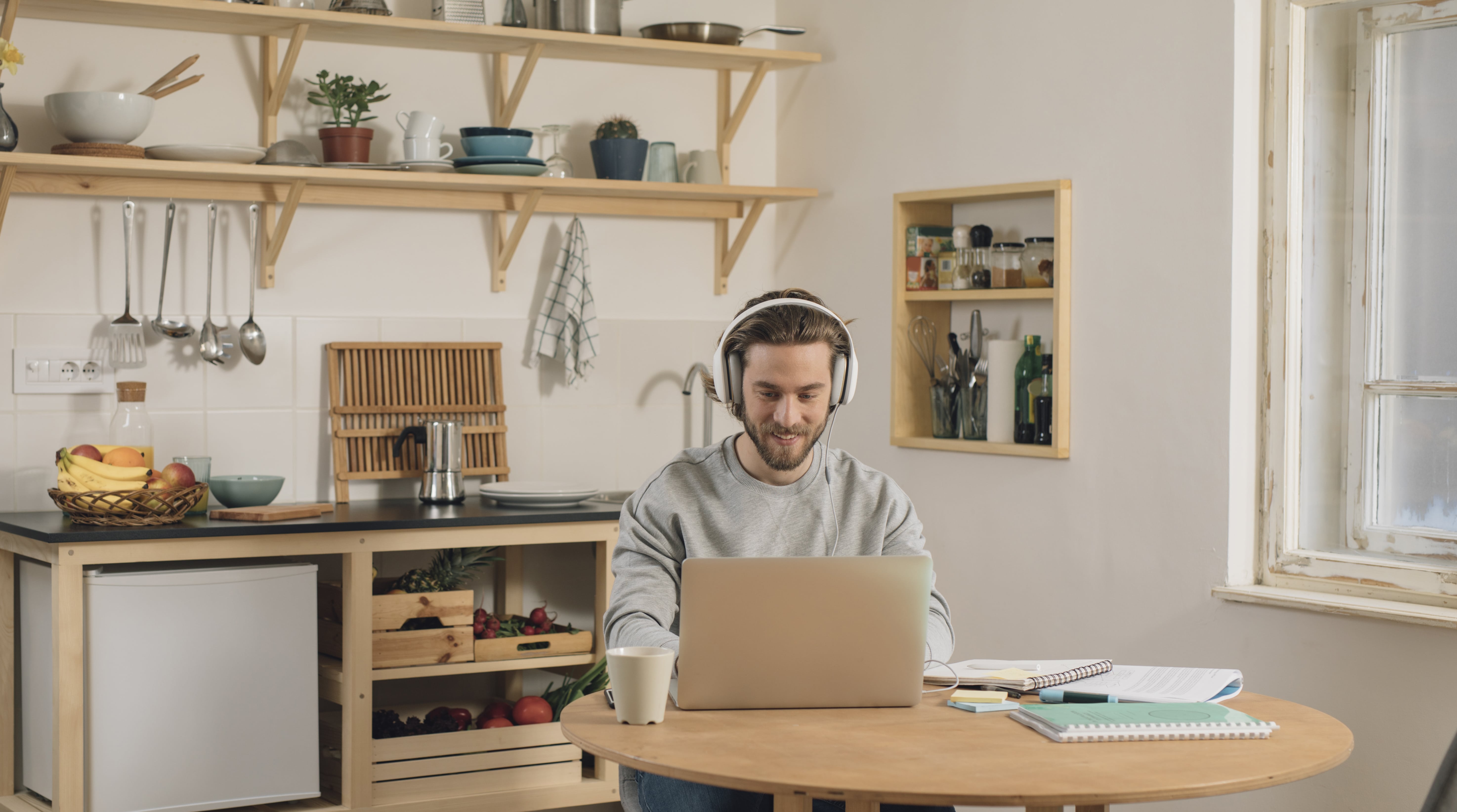 Man with headphones sitting at his desk in front of a computer and learning French at his own pace with Berlitz Flex