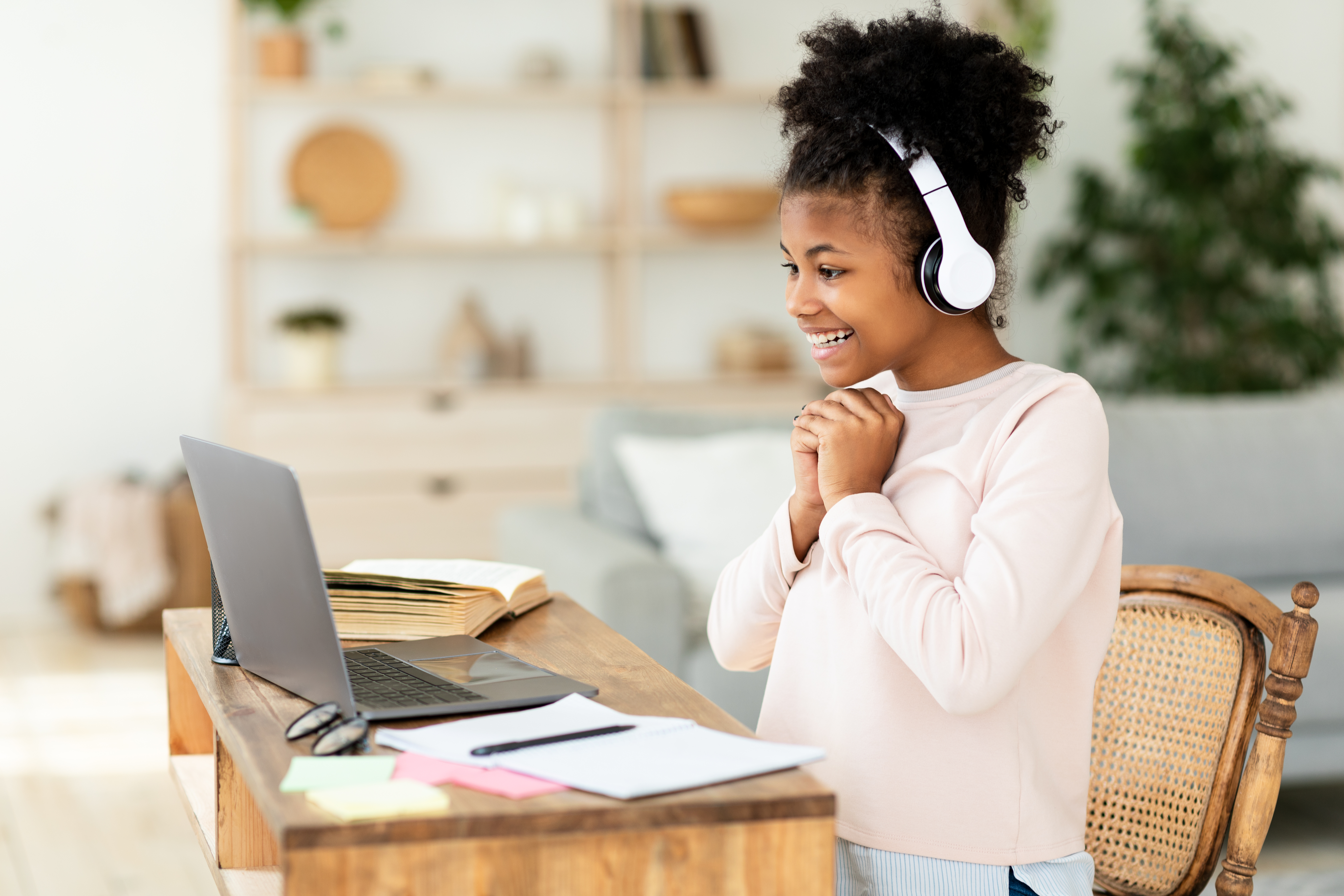 Girl with headphones smiling at her instructor during an online language course for kids and teens with Berlitz