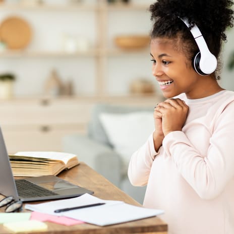 Girl with headphones smiling at her instructor during an online language course for kids and teens with Berlitz