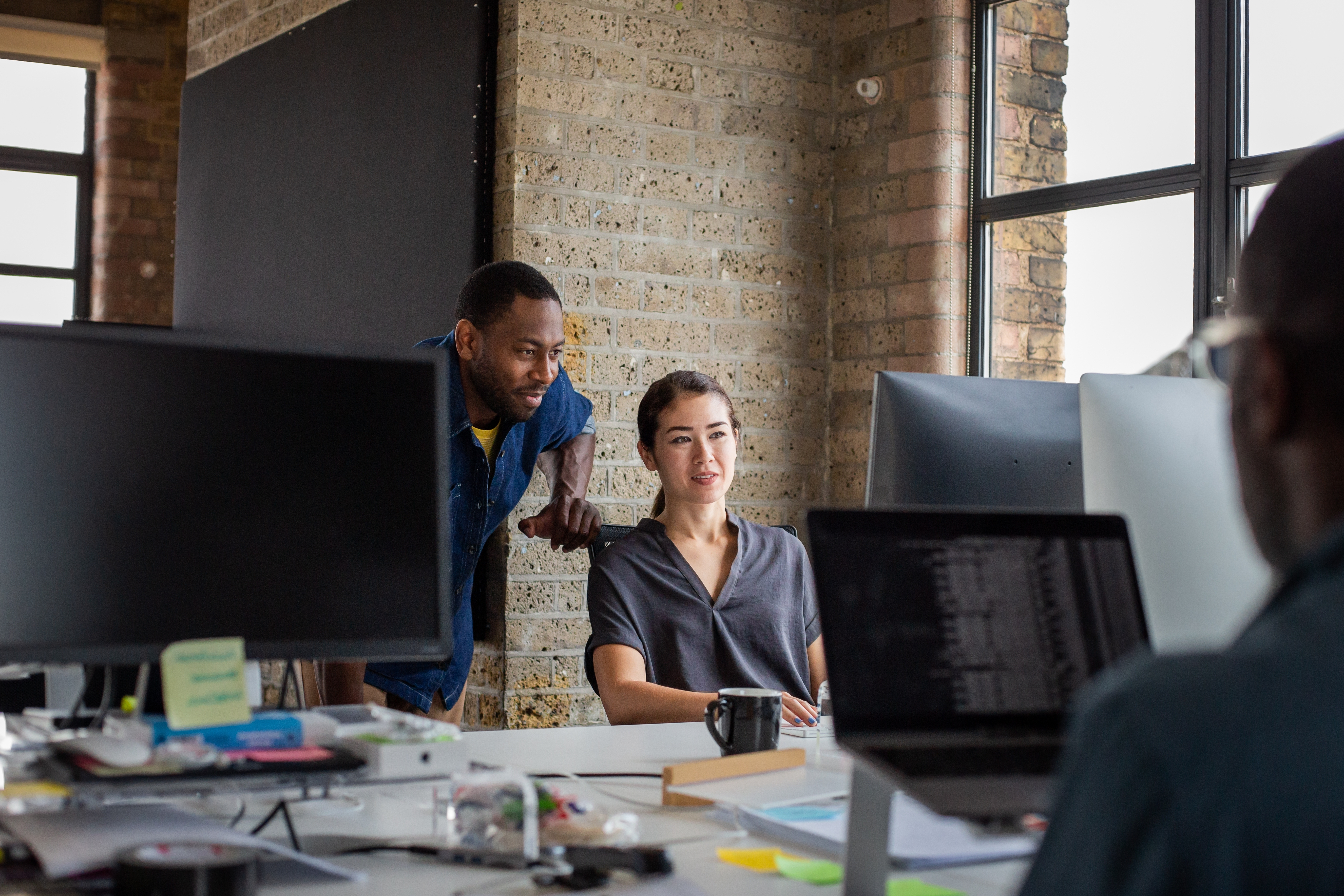Instructor talking to his student and looking at an exercise together on a computer during an SLE preparation course with Berlitz Canada