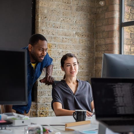 Instructor talking to his student and looking at an exercise together on a computer during an SLE preparation course with Berlitz Canada