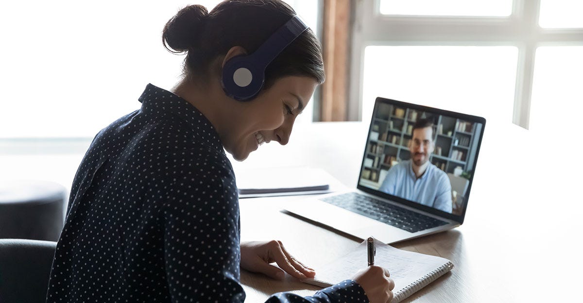 Woman with headphones making notes during a private online lesson with an instructor