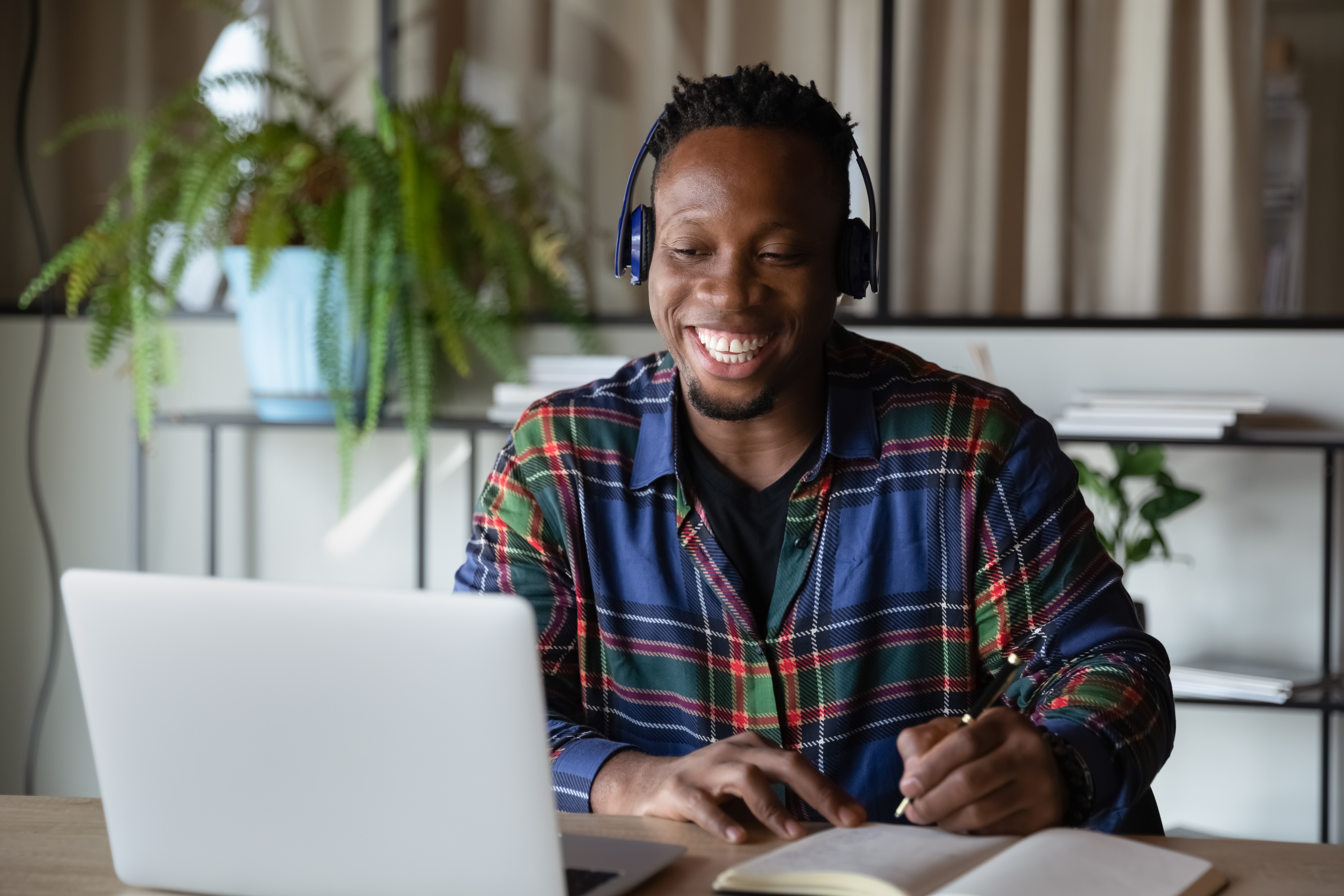 Man with headphones smiling while learning a language online with Berlitz Flex on his laptop