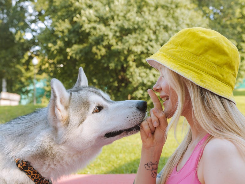 Woman in a bucket hat talking to her husky in German