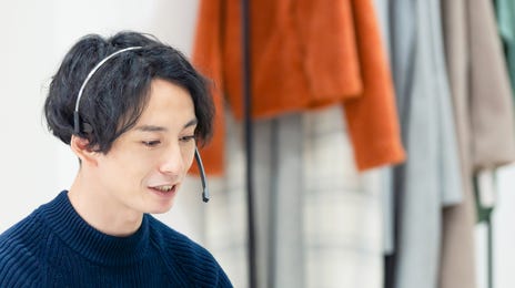 Man with headphones talking to his instructor during an online group language class with Berlitz that he is attending from his laptop