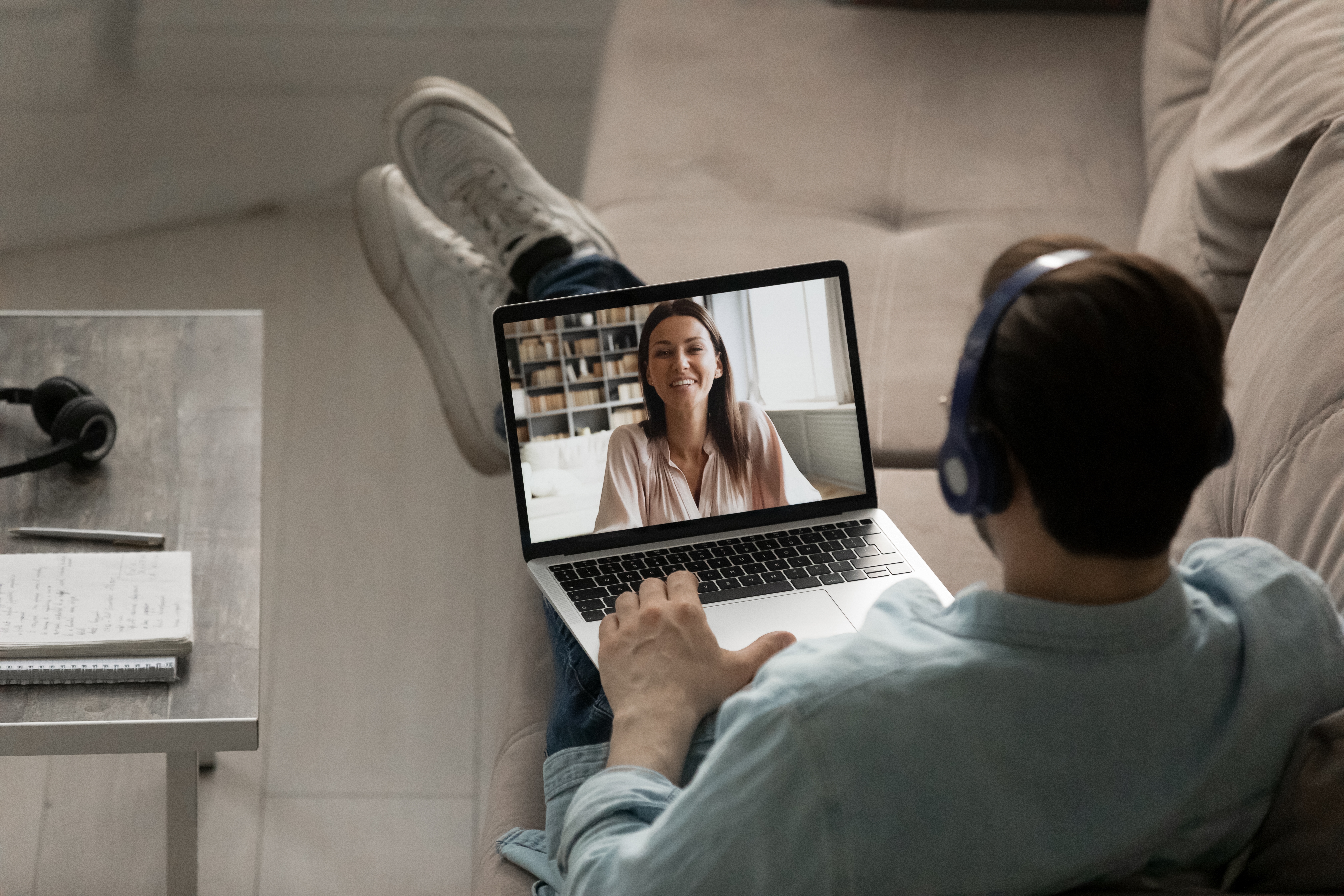 Man in headphones attending an online language class from his laptop