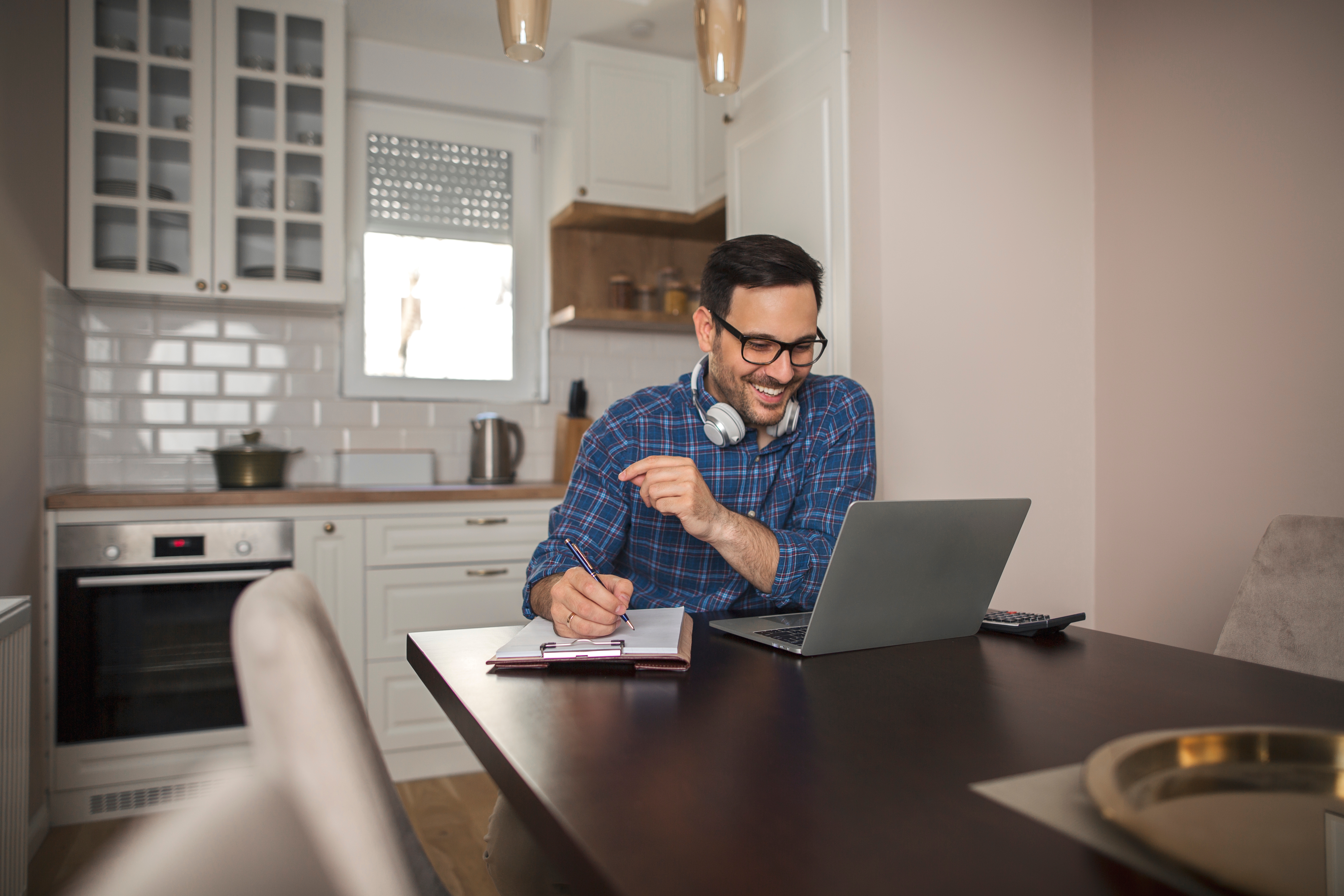 Man making notes during his online language class with Berlitz Regina that he is attending from home