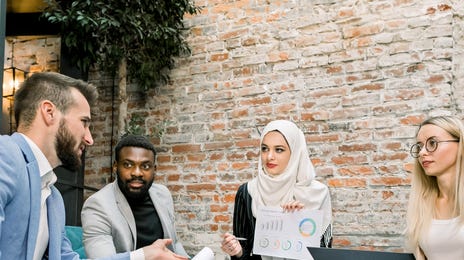 Team of coworkers sitting on a couch and listenining to their instructor during a business seminar with Berlitz Canada