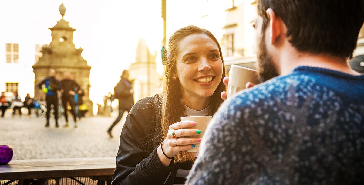 Couple on a date sipping coffee and talking to each other in German