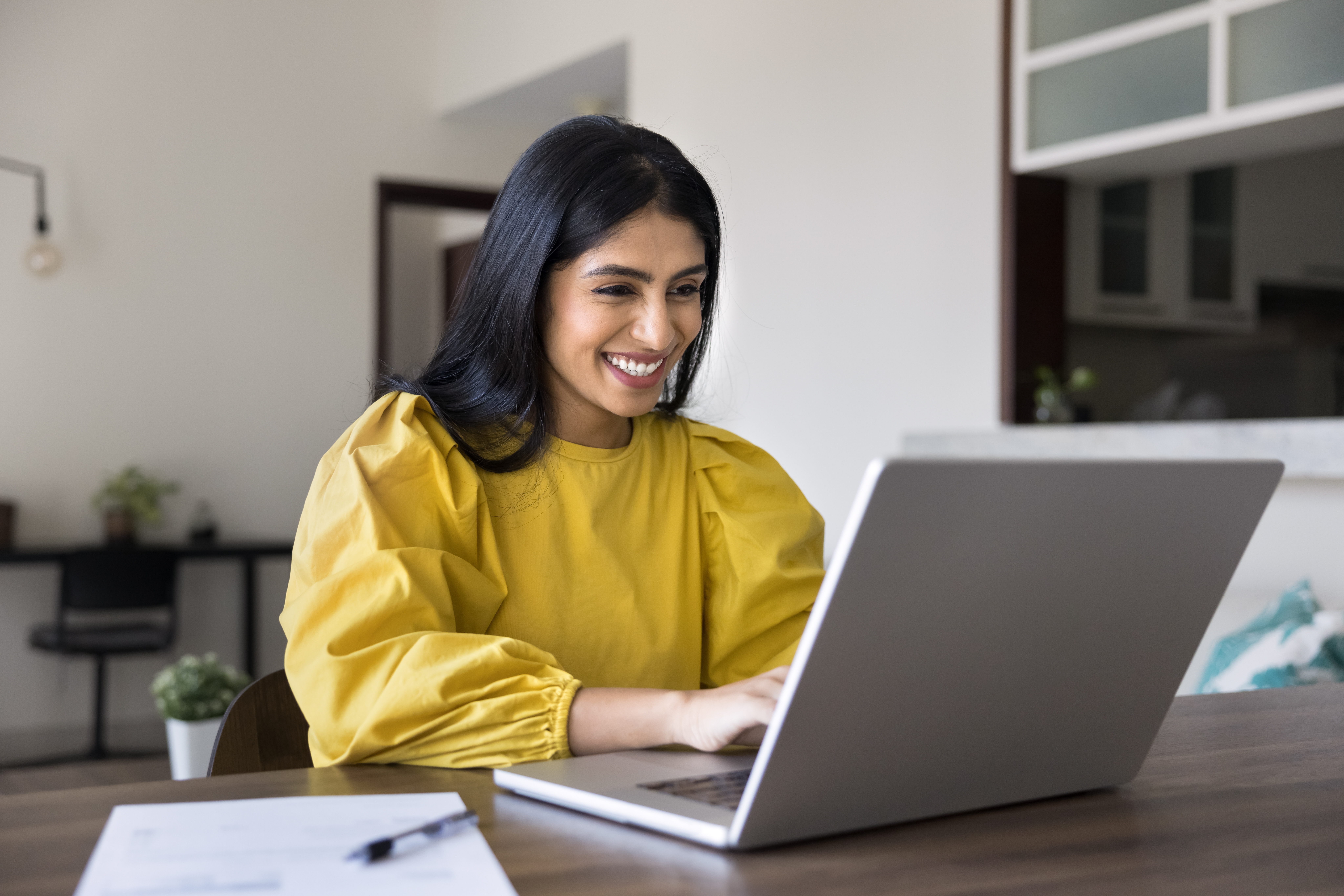 Woman smiling at her laptop while studying a language with Berlitz Flex