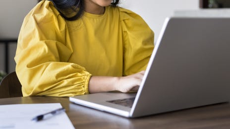 Woman smiling at her laptop while studying a language with Berlitz Flex