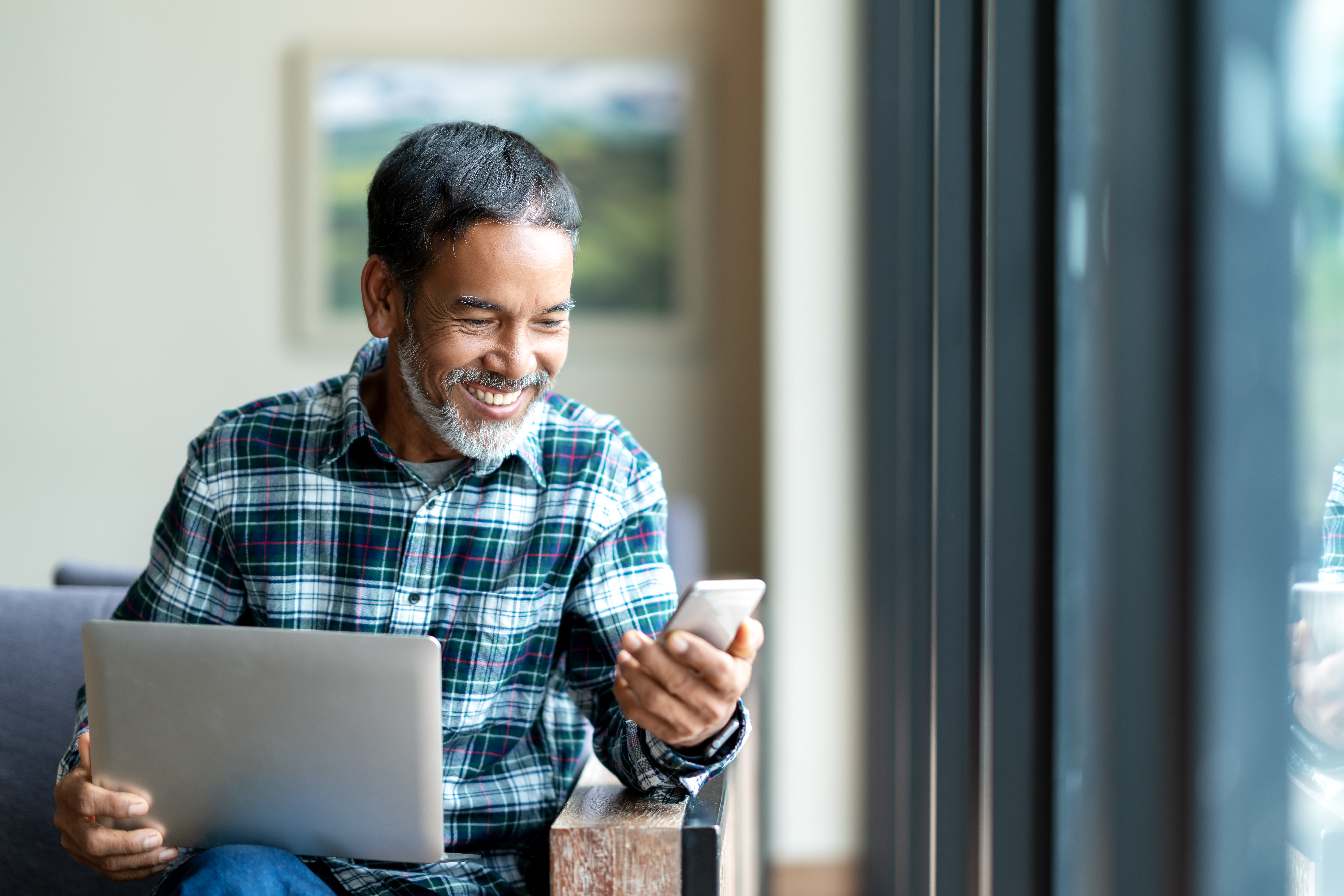 Man with a laptop checking out the Six-Week Challenge on his phone and smiling