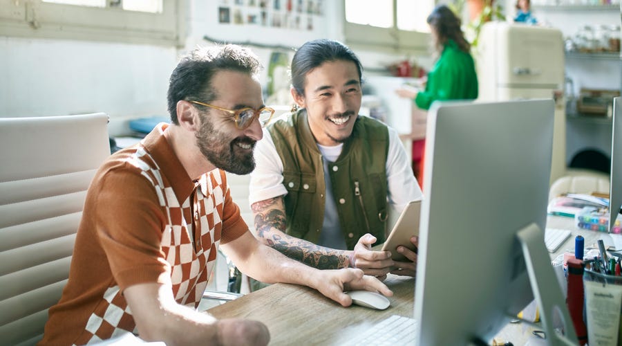 Two men sitting in front of a computer and attending an online group lesson with Berlitz
