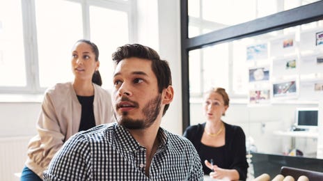 Group of coworkers in their workplace sitting at a table and attending a language lesson for adults with Berlitz