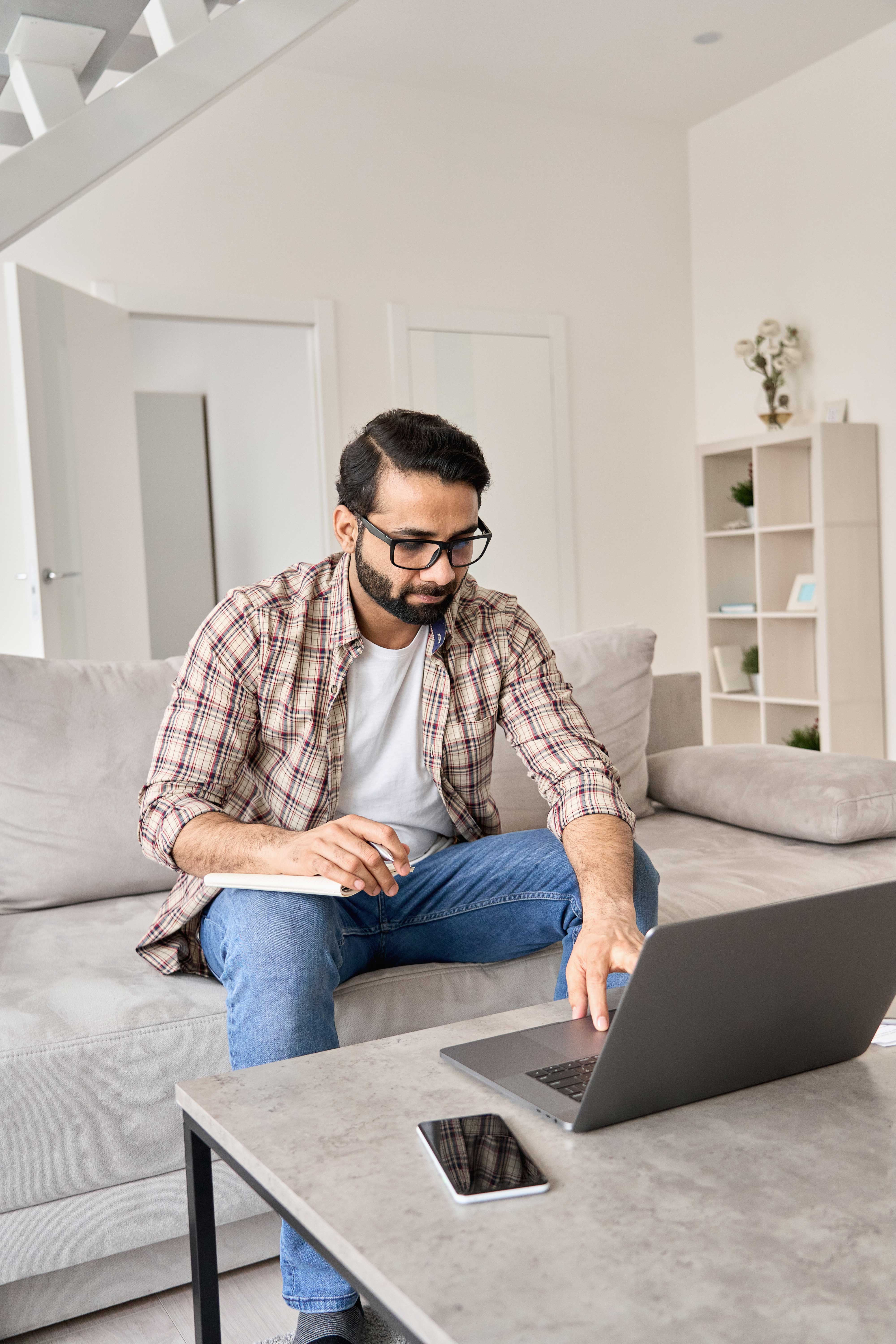 Man sitting in front of a laptop and making notes while preparing for his Test of Reading Comprehension
