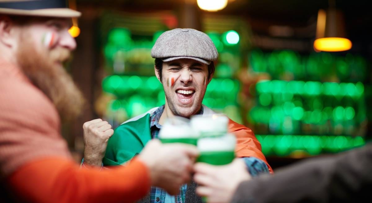 Man smiling at his friends and saying absolutely for a new round while they drink their beer
