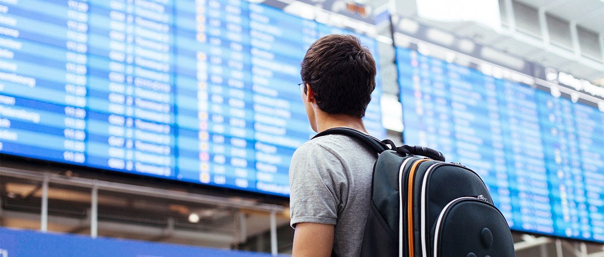 Man with a backpack checking the flight schedule at the airport