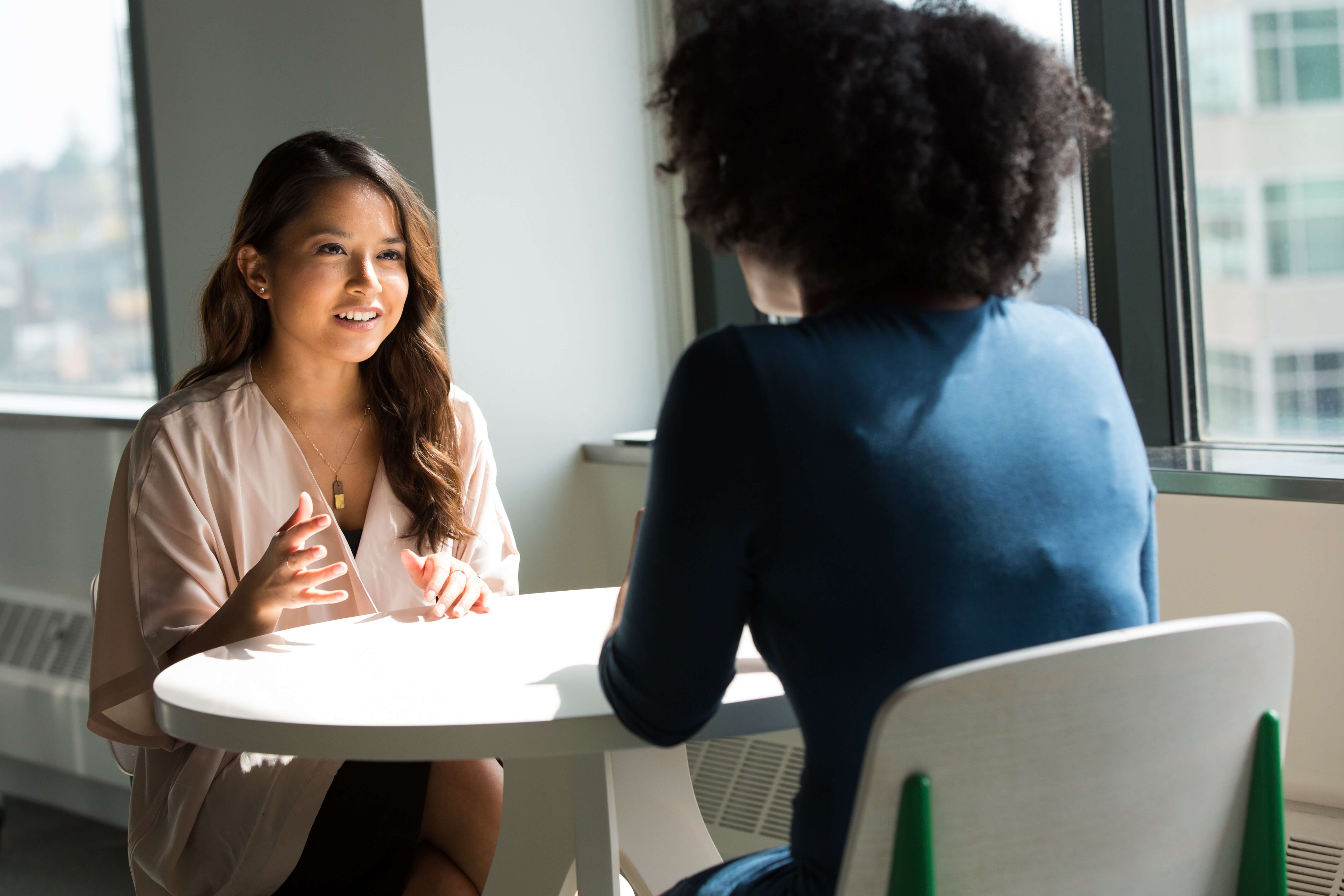 Two women sitting at a table and talking about the French alphabet