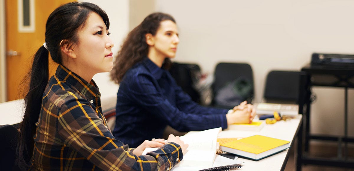Students sitting at a desk and paying attention to their instructor during a German lesson