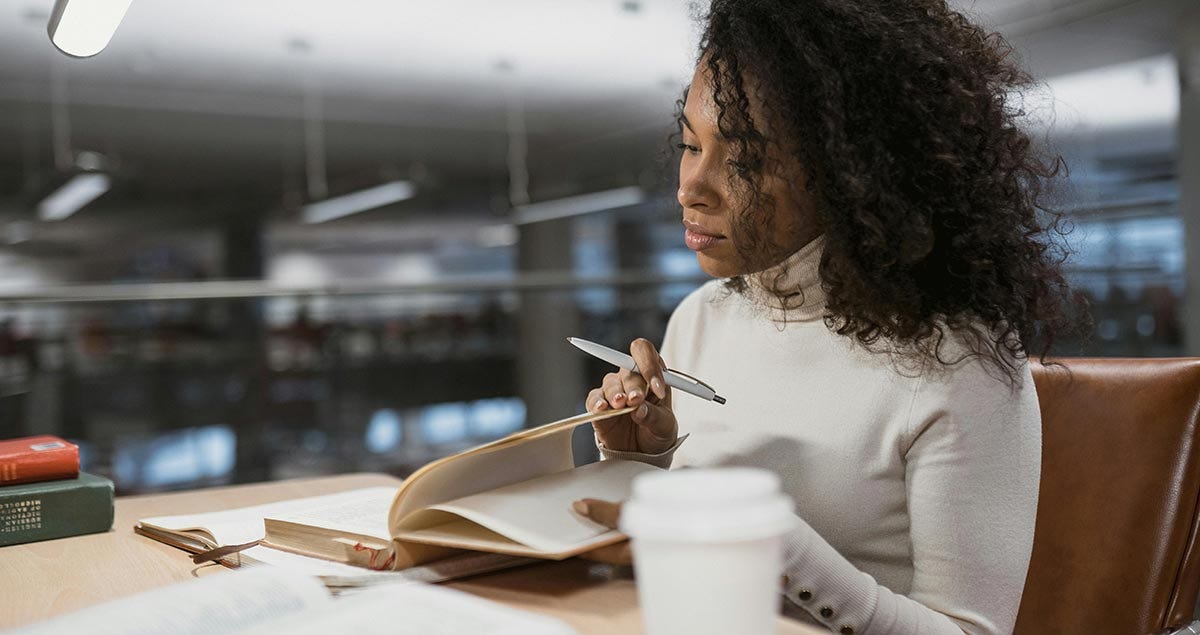Woman sitting at a table and making notes while studying the Spanish genders