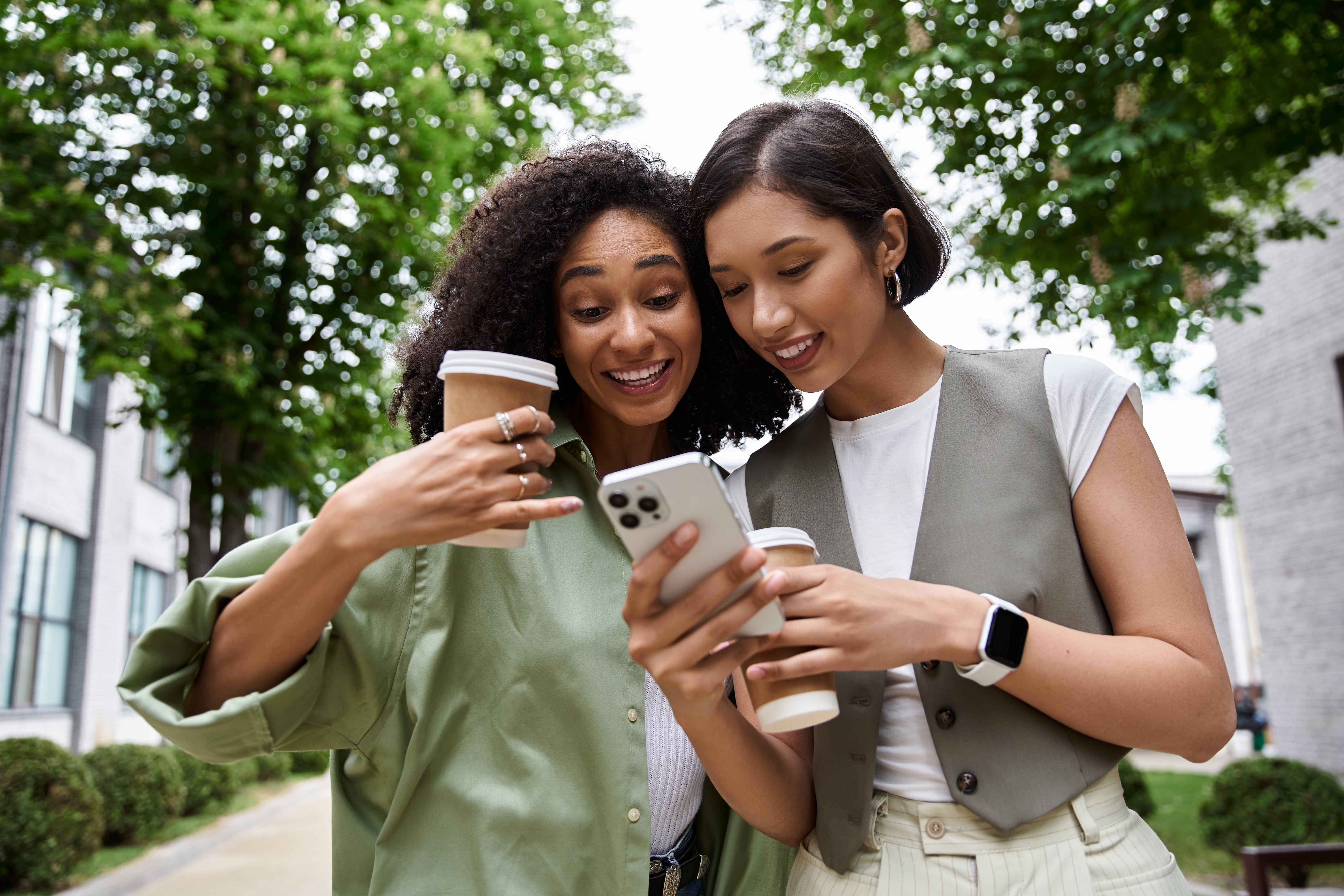 Two friends holding a phone and reading about online semi-private language classes with Berlitz while smiling
