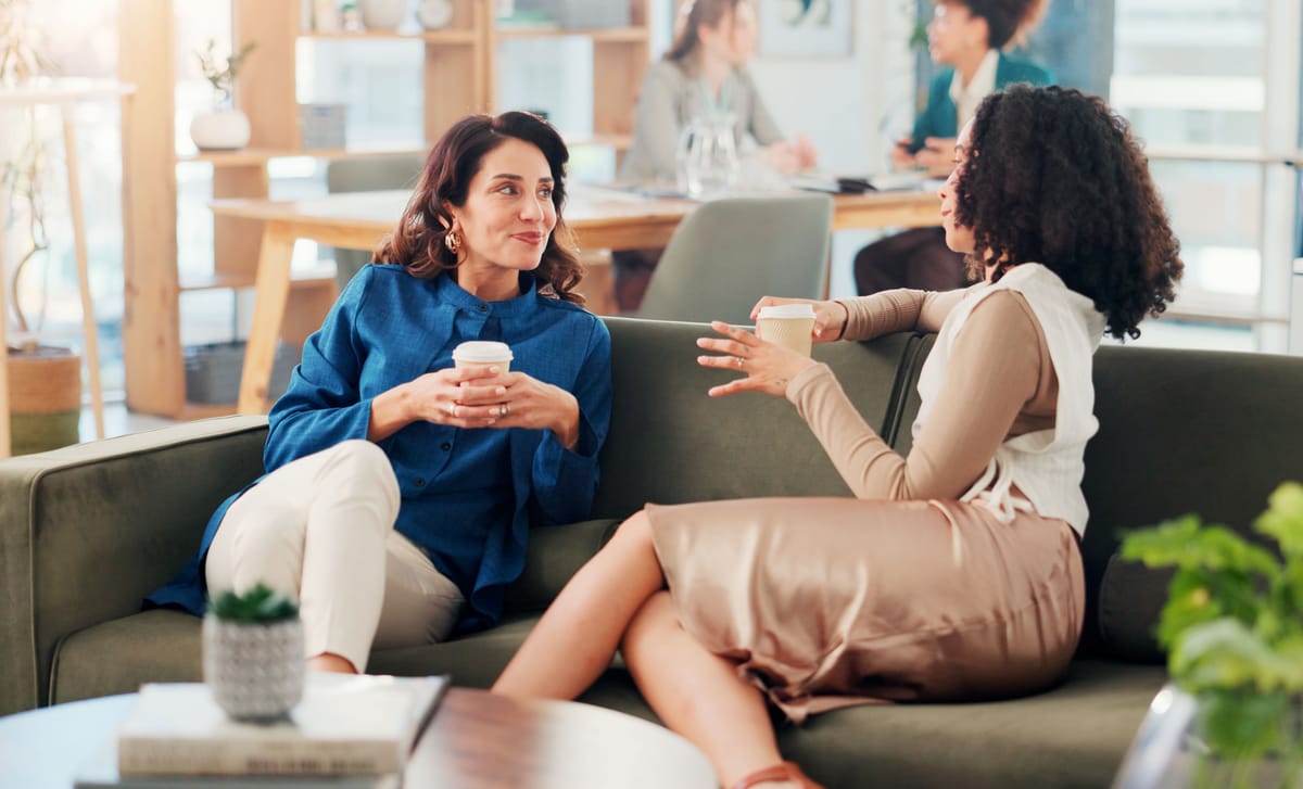 Two women at their workplace drinking coffee and chatting after their M&A Integration Language Training with Berlitz Canada